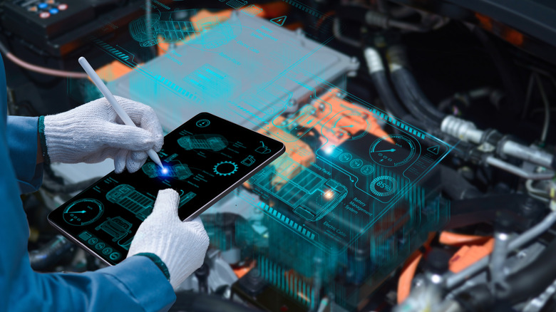 Автомеханик с помощью планшетного беспроводного сканирующего устройства для проверки системы двигателя ECU
