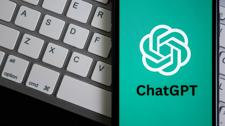 Логотип CHATGPT на телефоне за клавиатурой