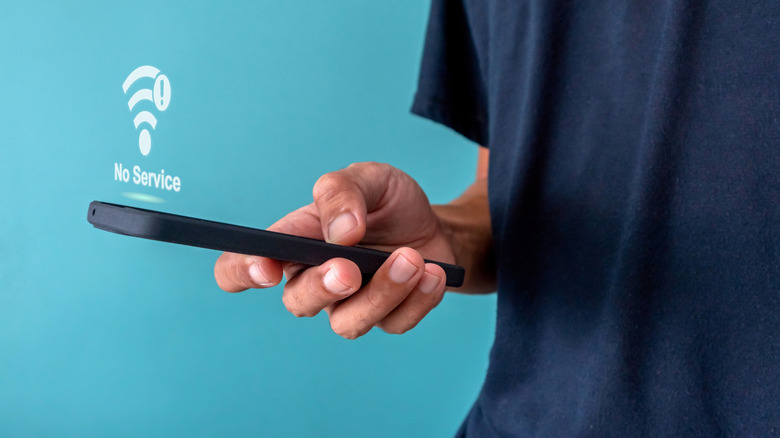 Человек держит телефон без сигнала
