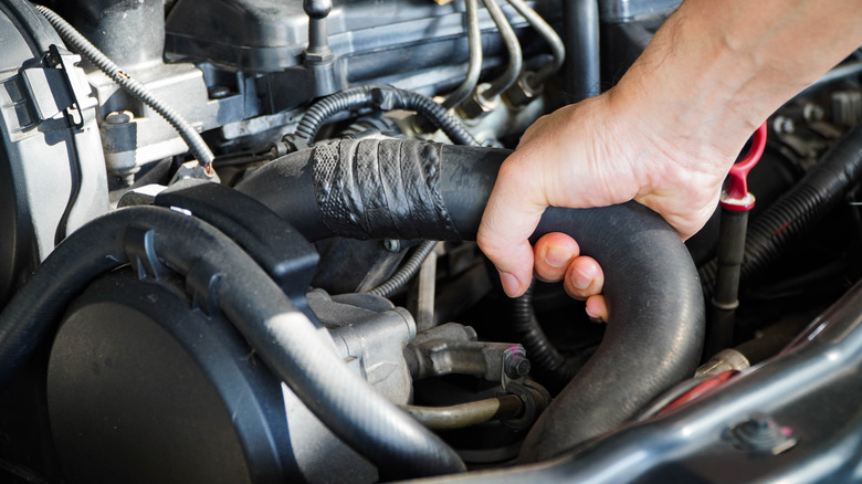 Человек, работающий на старом шланге радиатора