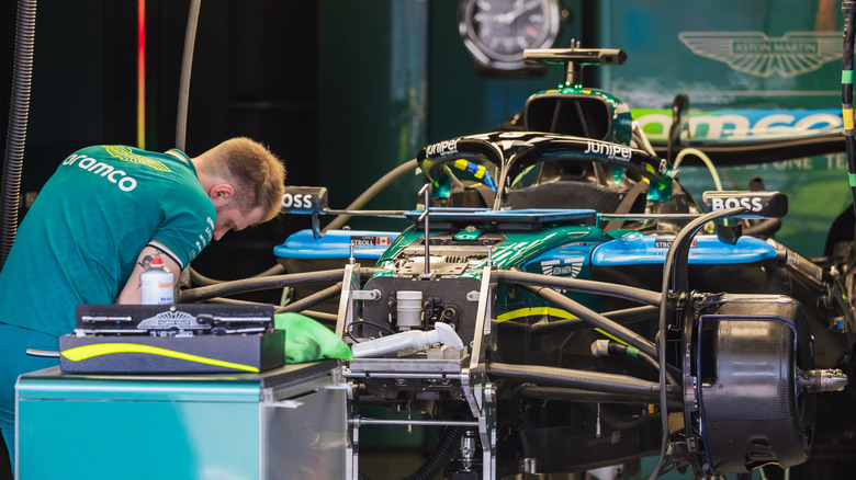 Aston Martin Mechanic, работая над подвеской в ​​гараже