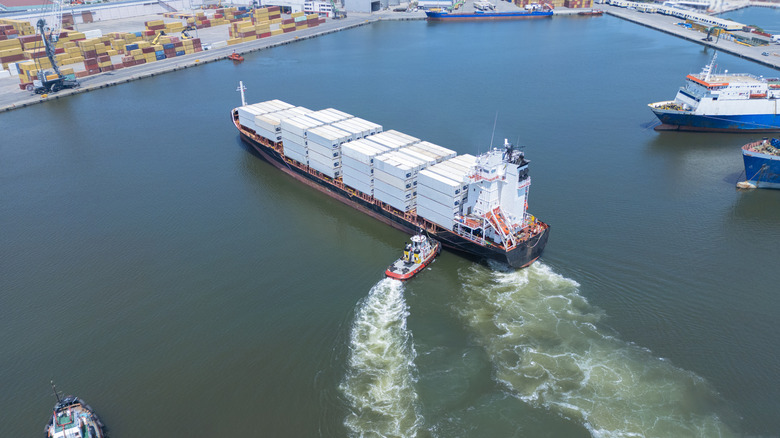 буксир, подталкивающий грузовой корабль в гавани