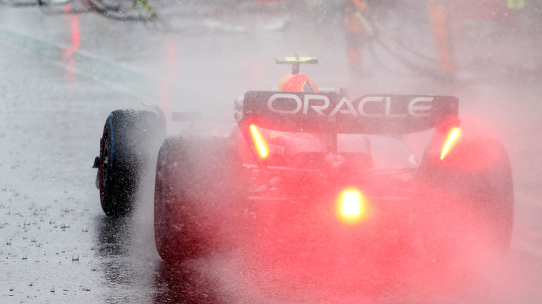 Red Bull F1 автомобиль сзади под дождем в пит -лейн с красным светом освещена