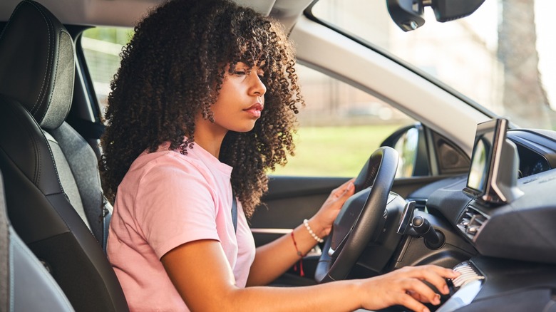 Женщина на сиденье водителя нажимает на циферблате