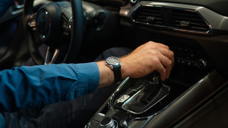 Крупный план человека, сдвигая автоматическую коробку передач автомобиля