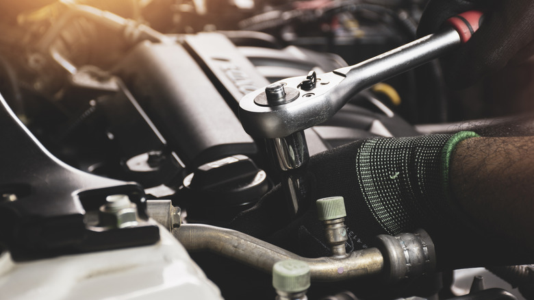 Человек, использующий гаечный ключ на двигателе