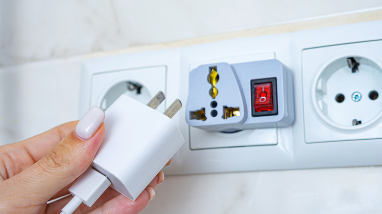 Человек, готовящийся к подключению American Charger Plug к адаптеру на европейском розетке