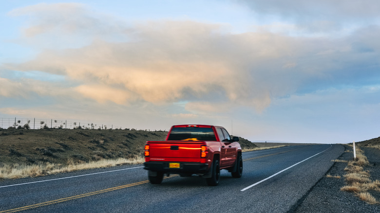 Одинокий красный пикап, едущий по дороге по утрам