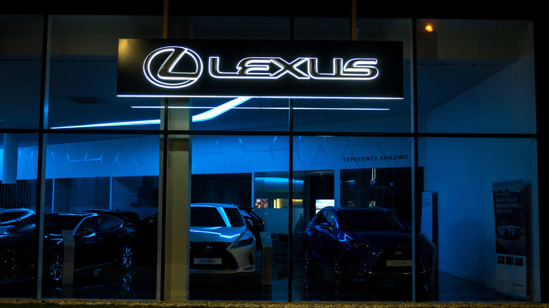Логотип компании Lexus на внешней стороне дилерского центра Lexus, снятый ночью.