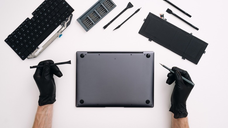 Человек, открывающий заднюю оболочку ноутбука