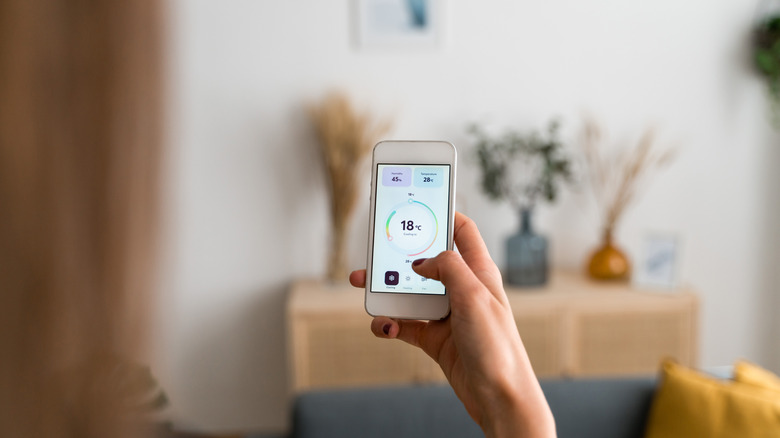 Человек, держащий смартфон, смотрящий на приложение для температуры