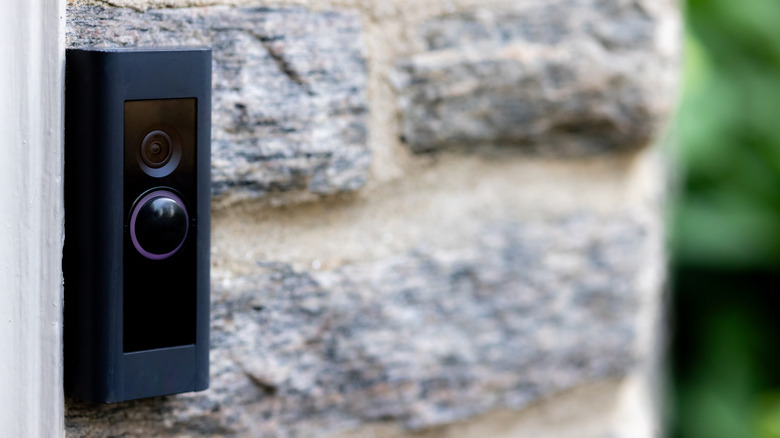 Камера черного дверного звонка, установленная на кирпичной стене