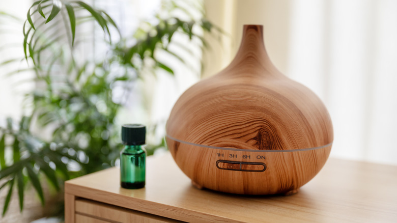 Круглый деревянный диффузор масла рядом с зеленой бутылкой