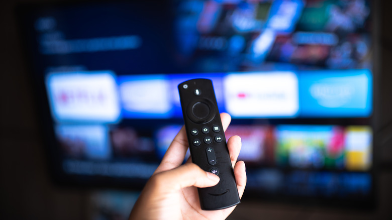 Amazon Fire TV Stick с телевизором на заднем плане