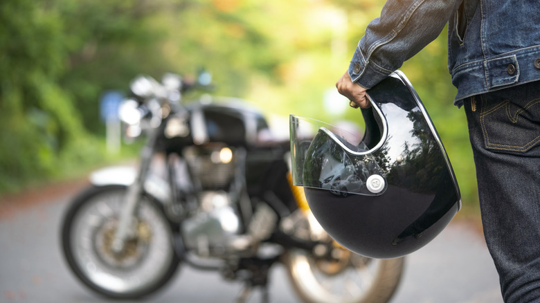 Человек, держащий шлем и идет к мотоциклу