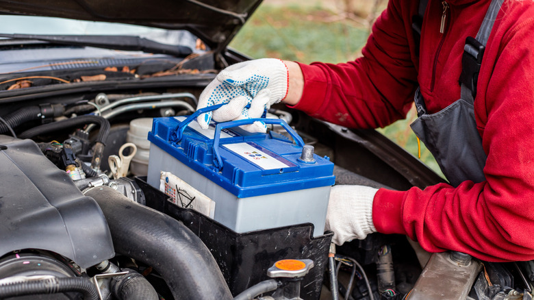 Механик вынимает автомобильную батарею