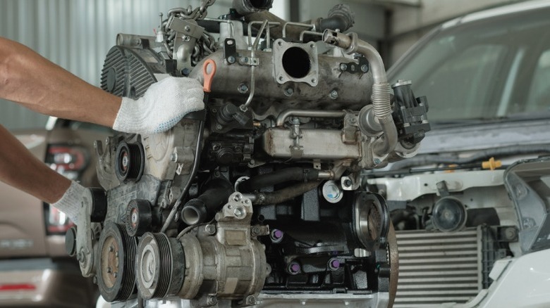 Механик снимает старый двигатель с автомобиля и готовится к новому двигателю