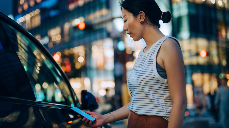 Человек, открывающий автомобиль, используя смартфон