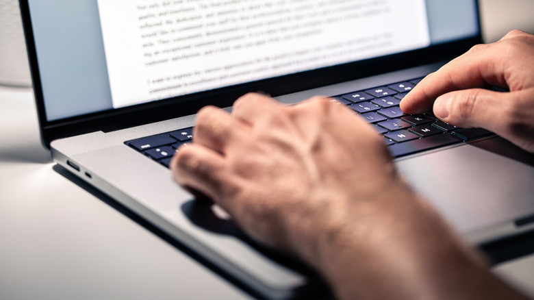 Человек, набирающий на ноутбук клавиатуру