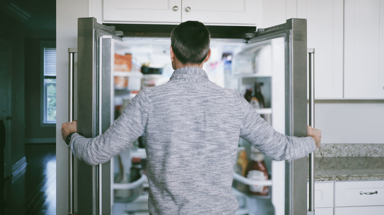 Человек, заглядывающий в холодильник.