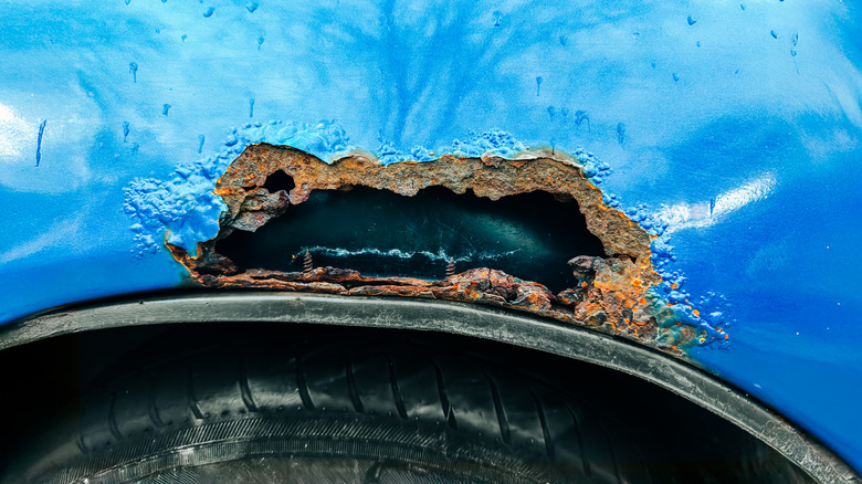 Большая дыра ржавчины в стороне машины