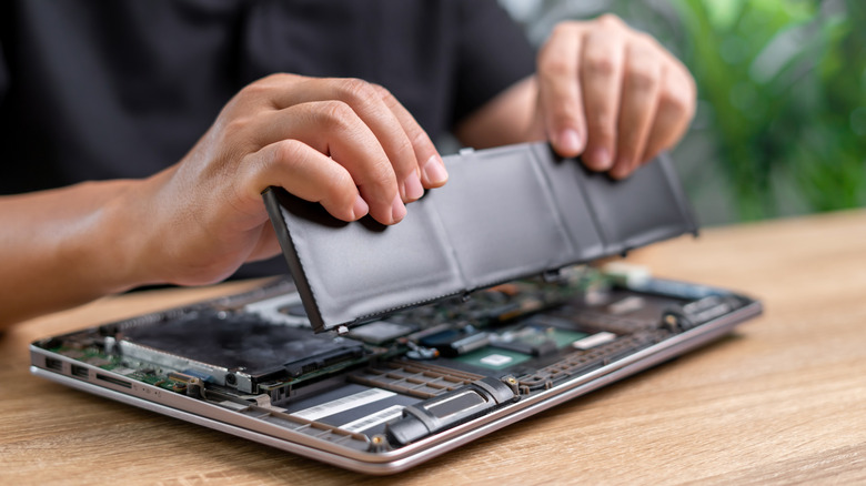 Техник помещает новую батарею в ноутбук