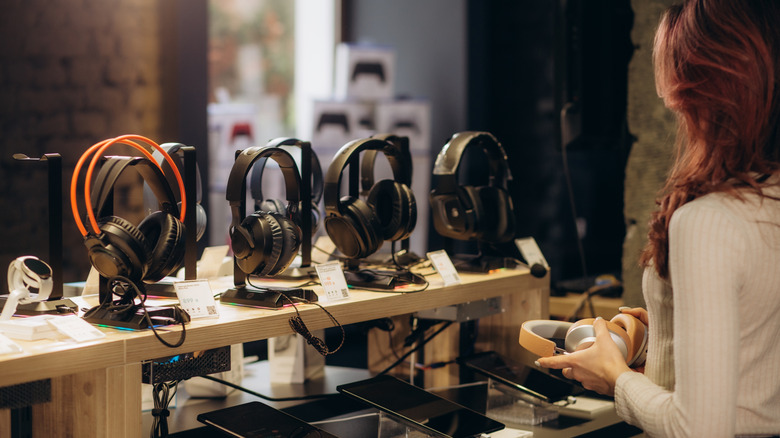 Женщина покупает наушники в магазине