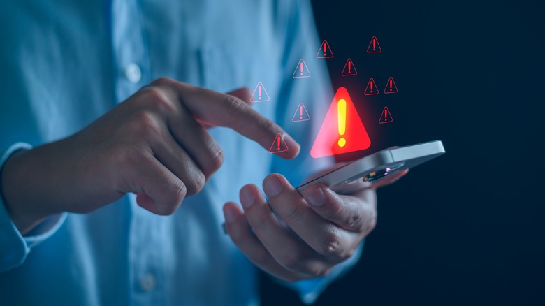Человек, касающийся смартфона с помощью графики предупреждающей знаки