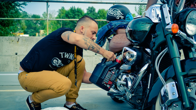 Байкер, меняющий масло на своем велосипеде в Harley-Davidson