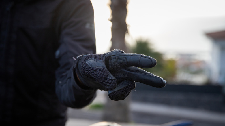 Крупным планом байкера в перчатках, показывающих знак V