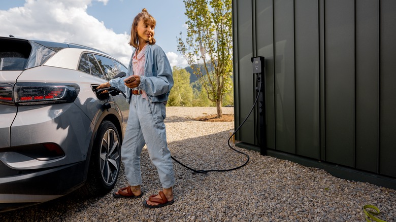 Человек, заряжающий электромобиль