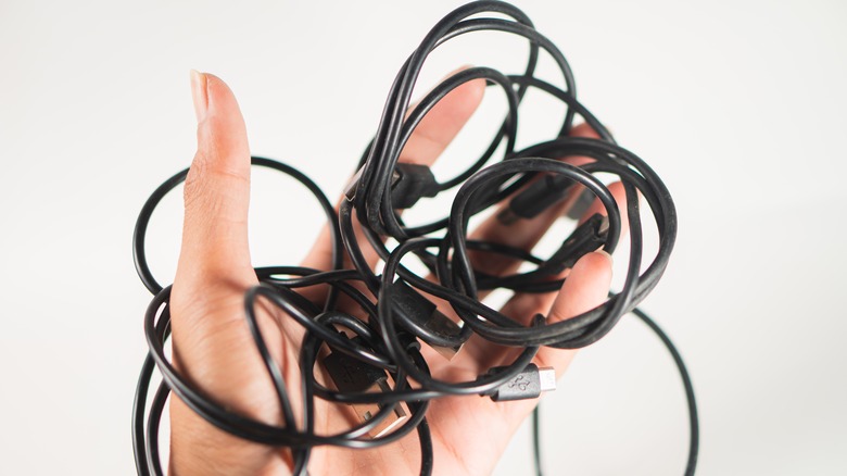 Левая рука с запутанным черным USB -кабелем