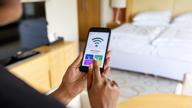 Человек, настраивающий настройки маршрутизатора Wi-Fi через свой смартфон.