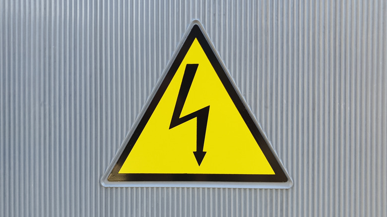 Предупреждающий знак Hugh напряжения на стальной стене