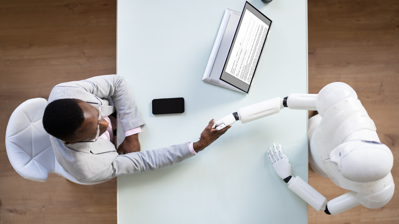 Человек пожимает руку роботу