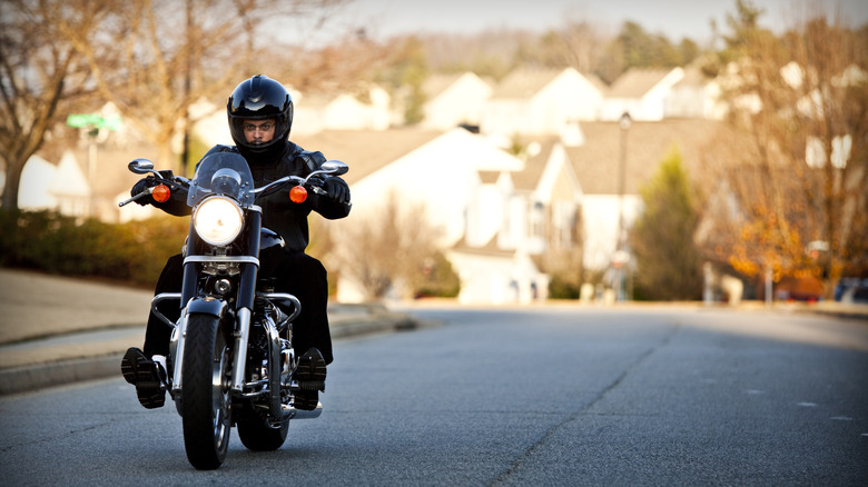 Короткий гонщик в шлеме на мотоцикле крейсера