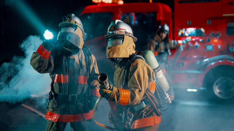 Два пожарных возле пожарной машины