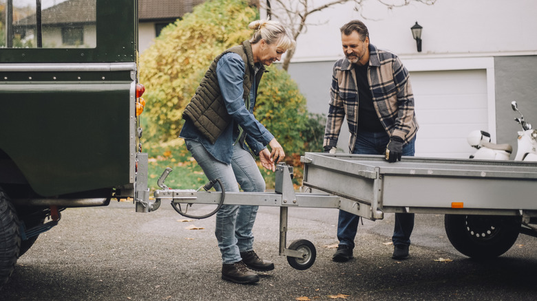 Мужчина и женщина прикрепляют трейлер к буксирному засущке