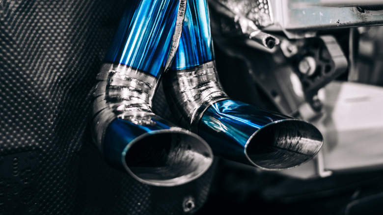 Пользовательская выхлопная система титана на автомобиле среднего двигателя, показывающая синюю трубу и замысловатые сварки