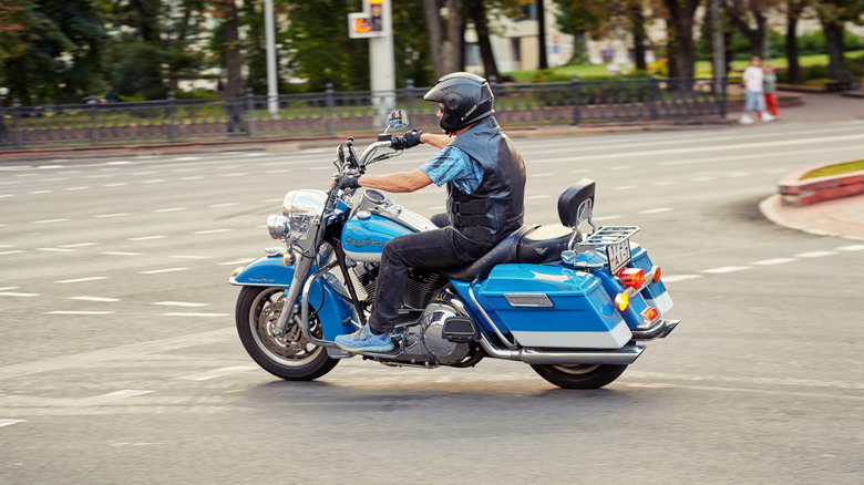 Человек, который делает левый поворот через перекресток, едущий на Blue Harley Davidson Road King