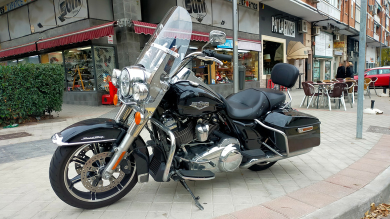 Black Harley Davidson Road King, припаркованный на улице на тротуаре перед магазинами
