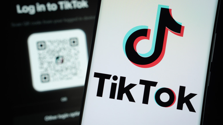 Tiktok отображается на экране смартфона, в фоновом режиме видны другой телефон.
