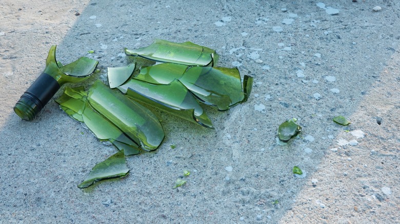 Большие осколки сломанной зеленой стеклянной бутылки на земле