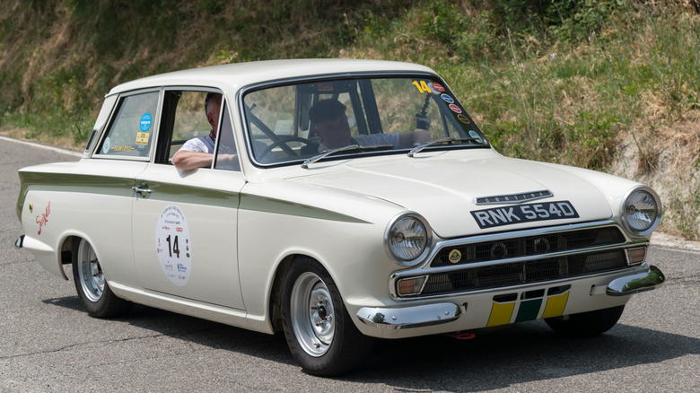 Лерсский белый Ford Cortina Lotus с водителем и пассажиром на дороге