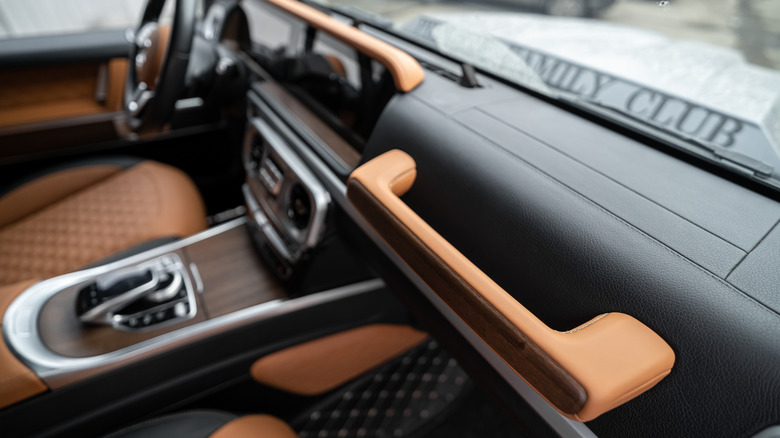 Изображение интерьера класса Mercedes Benz G с ручкой захвата приборной панели в фокусе.