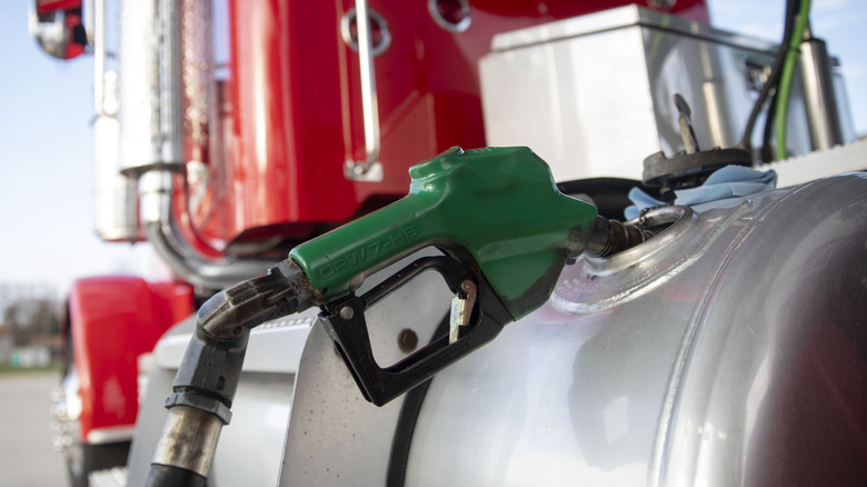 Обзор не присматривает за не присматриваемым зеленым топливным сопло в топливном баке красного полузащитного трактора.