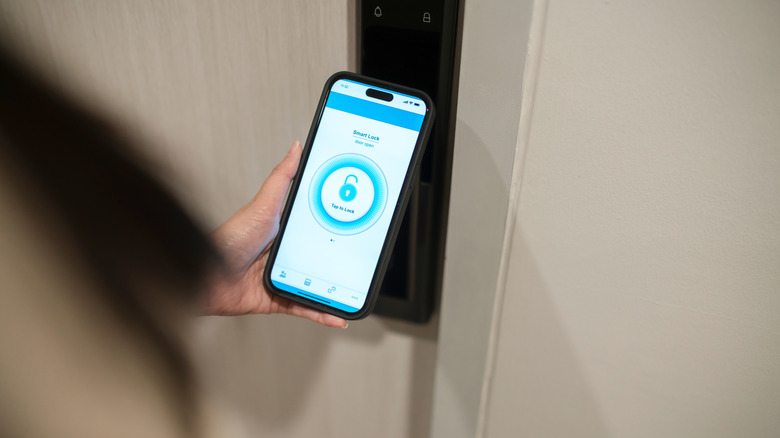 Человек, держащий смартфон рядом с дверью безопасности с символом блокировки на телефоне