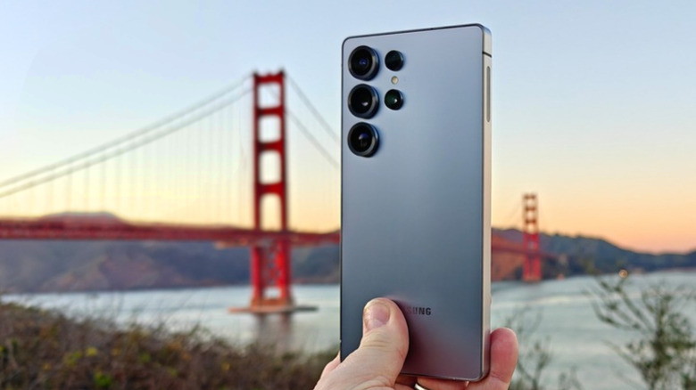 Рука держит Samsung Galaxy S25 Ultra перед мостом Золотых Ворот