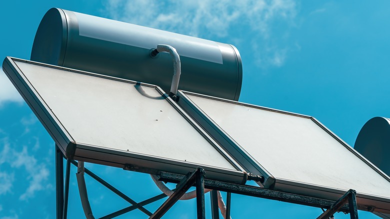 Крупный план солнечной системы водонагревателя на крыше под прозрачным голубым небом.