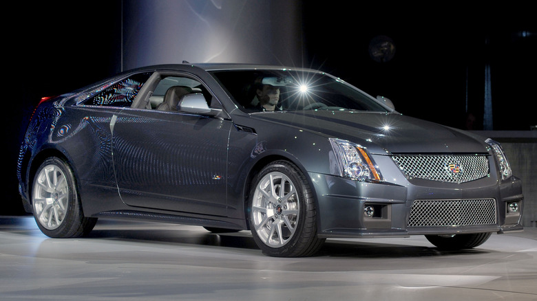 Серый Cadillac CTS-V Coupe на автомобильной выставке, спереди 3/4.